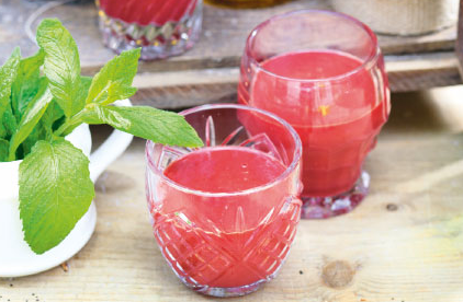 KI generiert: Zwei Gläser mit rotem Saft und ein Topf mit frischen Minzblättern auf einem Holztisch.